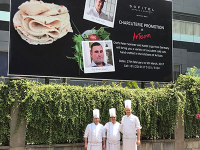 Metzger Sommer vor dem Hotel im Hintergrund eine riesige Werbewand für die Wurstpräsentation