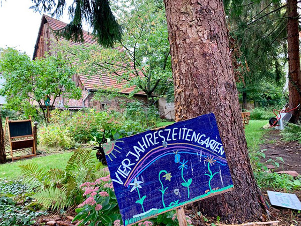 Ein Bauerngarten, eine Scheune. Schild: Vierjahreszeitengarten